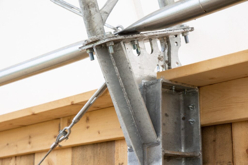 Close up view of purlins being attached to trusses that have been hot dip galvanized against the wood framing.