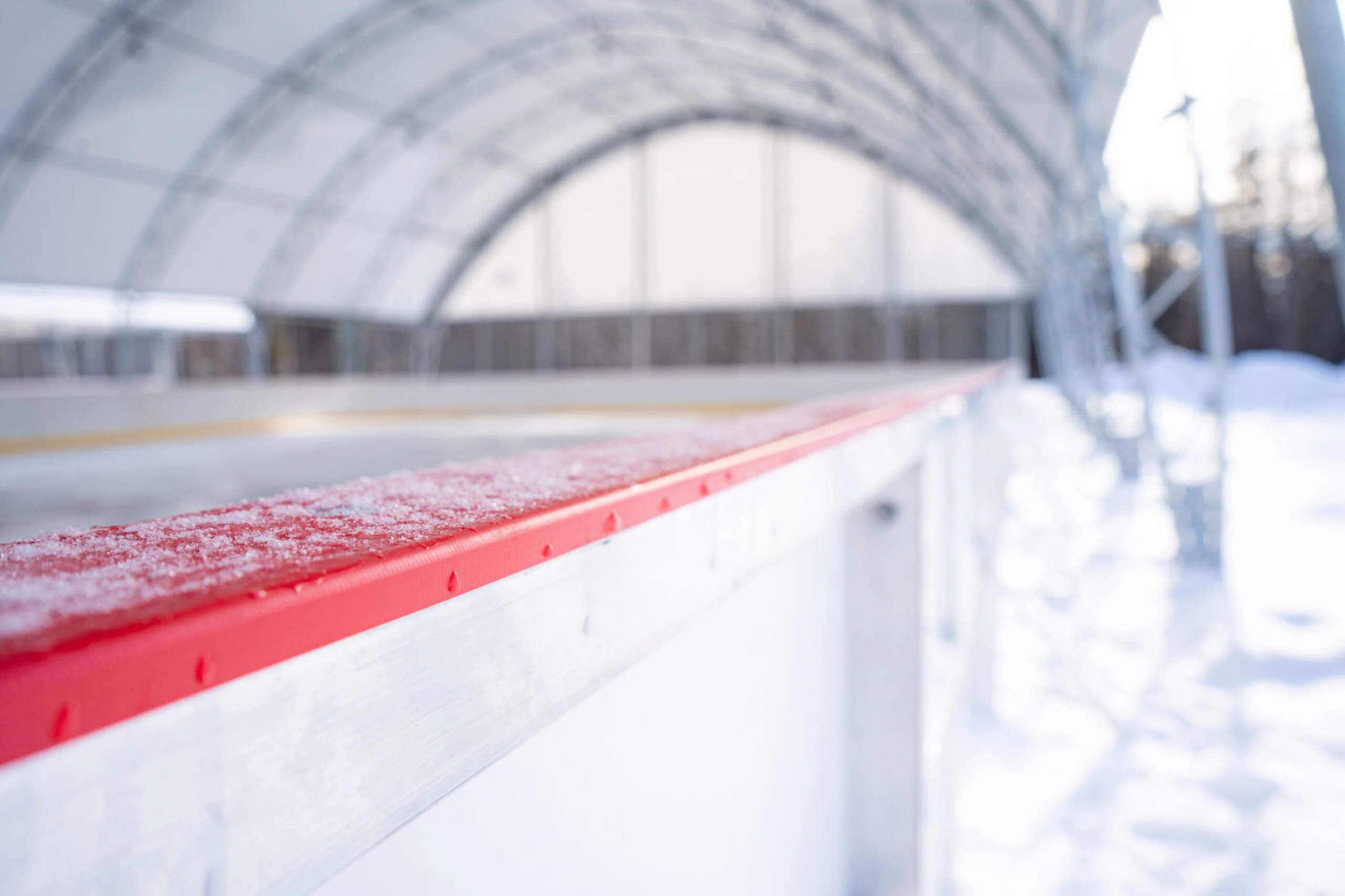 Fabric Ice Rink Building – Hockey Dasher Boards Interior - Britespan Hockey dasher boards inside a fabric-covered ice rink building with arched steel frame visible in background